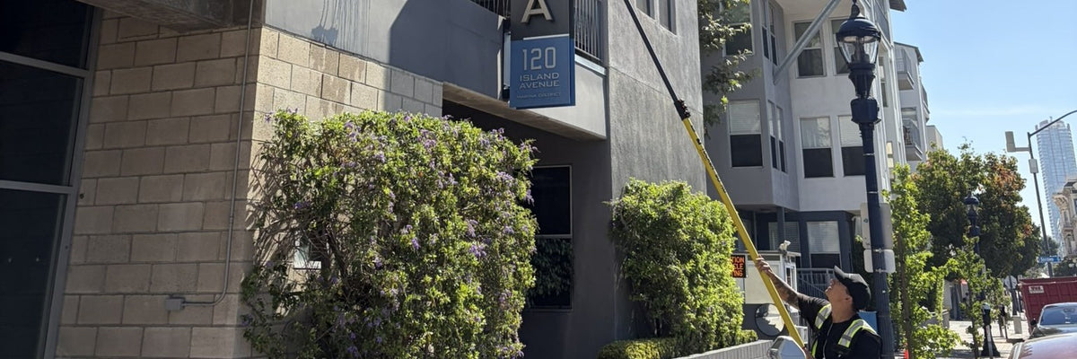 Top Tier Exterior Service technician cleaning windows with a water-fed pole at Atria apartments, 120 Island Ave, downtown San Diego